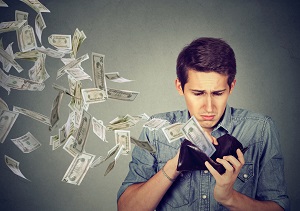 Young guy watching money fly out of wallet